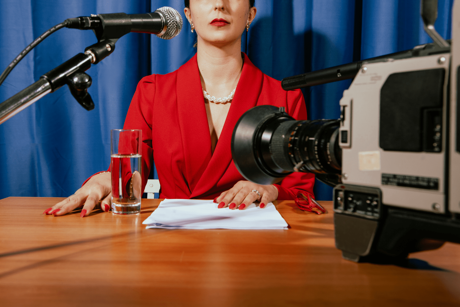 Woman in a red suit at a crisis comms press conference in front of mic and camera